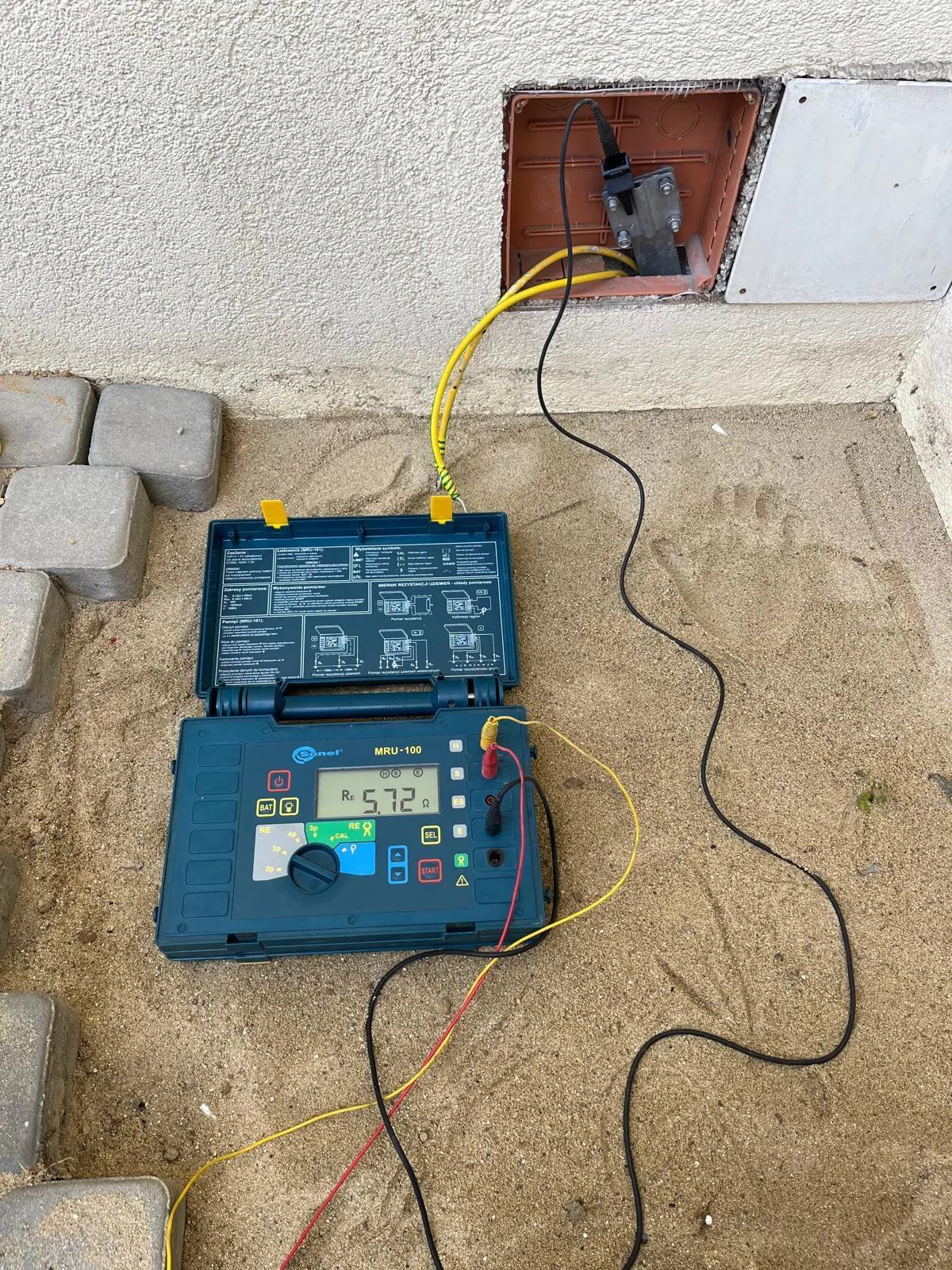 Miernik podczas sprawdzania instalacji przy budynku — Elektryk Lewandowski